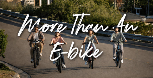 Four riders on E11EVEN electric bikes riding together on a sunny road beneath “More Than An E-bike” text