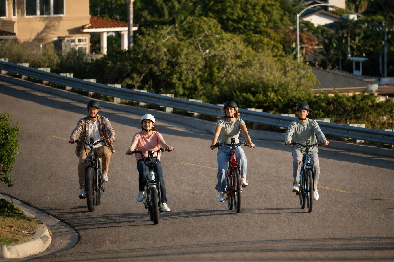 Four riders wearing helmets riding E11EVEN electric bikes together on a sunlit residential road
